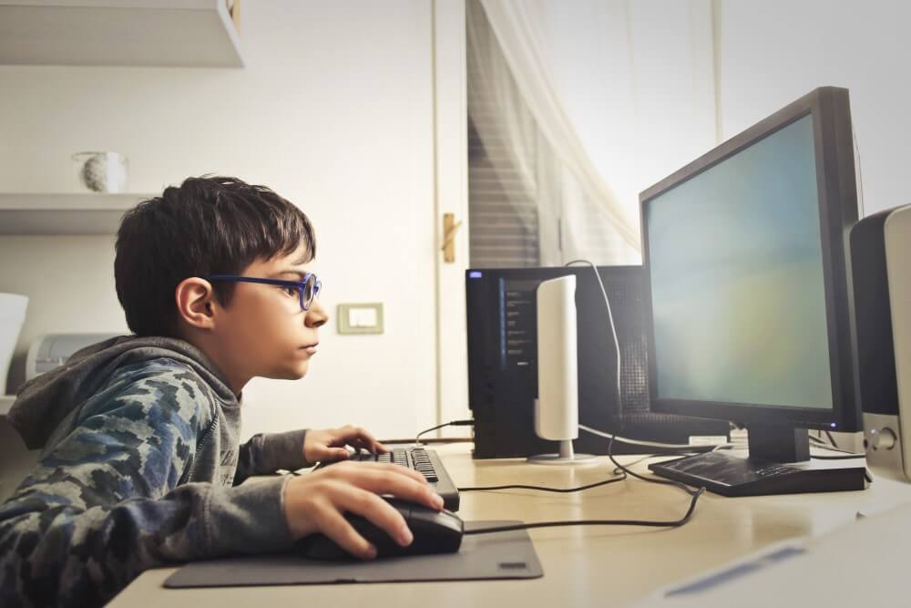 Criança aprendendo on-line à noite usando computador desktop na sala de  estar em casa criança jogando jogos de computador ou estudando no  computador pc jogador infantil na iluminação de néon noturna
